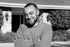 a black and white photo of a man with his arms crossed in front of a house