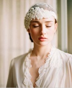 a woman wearing a white head piece with flowers in it's hair and her eyes closed