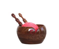 a wooden bowl with yarn in it and two knitting needles sticking out of the top