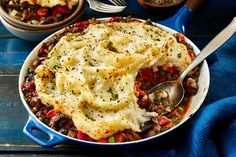 a casserole dish with mashed potatoes, meat and vegetables in it on a blue cloth