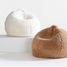 two bean bags sitting next to each other on top of a white surface and one is brown