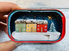 a hand is holding an ornament with small houses in it