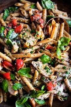 a plate full of pasta with spinach, tomatoes and parmesan cheese on top