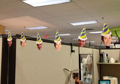 office cubicle decorated with birthday hats and photos hanging from the ceiling in an office