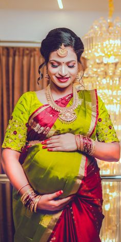 a woman in a green and red sari is holding her belly while looking down