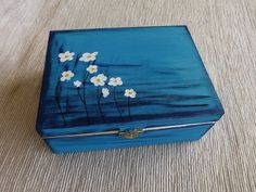 a blue box with white flowers painted on the lid sitting on top of a table