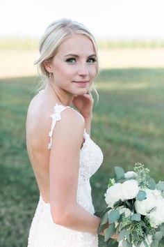 a beautiful blonde woman in a wedding dress holding a bouquet and looking at the camera