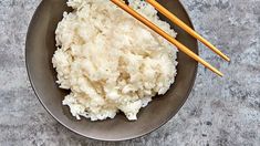 rice and chopsticks are in a bowl on the table with a gray surface