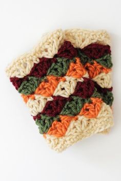 a crocheted dishcloth is shown on a white surface with orange, green and red stripes