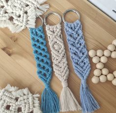 three crocheted key chains with tassels and beads on a wooden surface