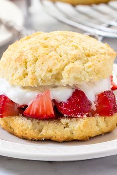 a biscuit with strawberries and whipped cream on it is sitting on a plate