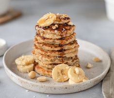 a stack of pancakes with bananas and nuts on a plate next to a glass of milk