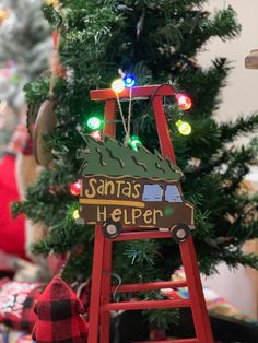 a christmas tree is decorated with lights and a sign that says santa's helper