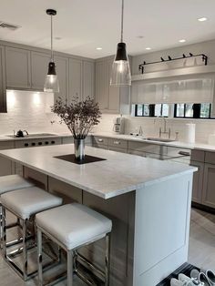 a kitchen island with stools in front of it and lights hanging from the ceiling