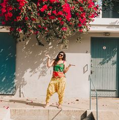 a woman standing on steps in front of a building with red flowers hanging from it