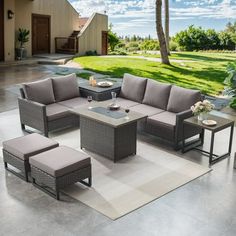 an outdoor patio furniture set with grey cushions and table on concrete flooring next to grassy area