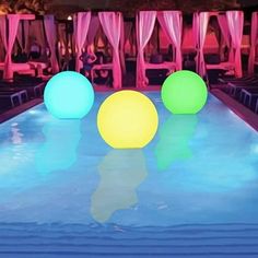 three glowing balls sitting on top of a swimming pool