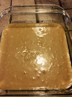 a glass dish filled with batter on top of a wooden table next to an oven mitt