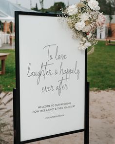 a sign that says to love laughter and happily ever after with flowers on it in front of a grassy area