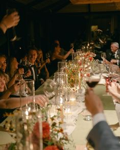 a group of people sitting at a long table with wine glasses in front of them