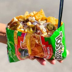 a person holding up a bag of chips and salsa