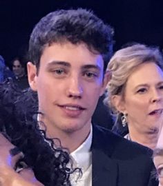 a man in a tuxedo standing next to a woman