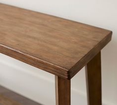 a wooden table sitting on top of a hard wood floor next to a white wall