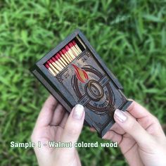 someone holding up a match box with matches in it and the words sample 1 - walnut colored wood