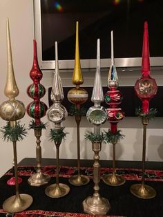 an assortment of glass and metal candlesticks on display in front of a flat screen tv