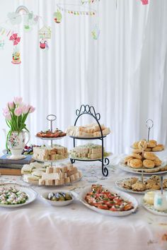 a table topped with lots of food next to a white drapes covered wall behind it