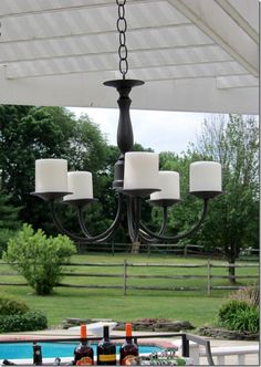 a chandelier hanging from the ceiling in a yard with grass and trees behind it