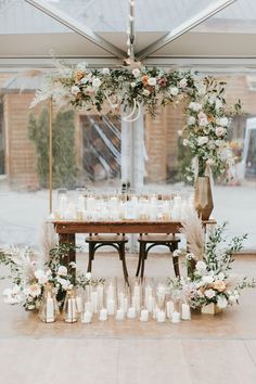 a table set up with candles and flowers in front of a large glass window at a wedding