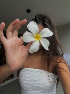 a woman holding a flower in front of her face