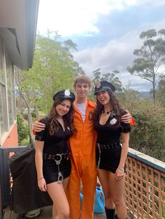 three people dressed up in costumes posing for a photo on a deck with trees and mountains in the background