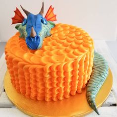 a cake decorated with an orange and blue frosting dragon head on top of it