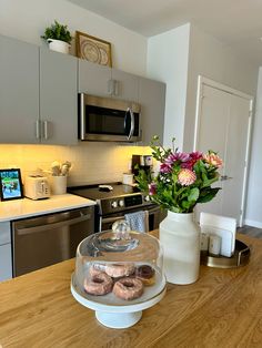 donuts are sitting on a cake plate in the middle of a kitchen countertop