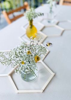 three vases filled with flowers sitting on top of a white tablecloth covered table