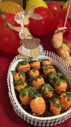 a bowl filled with chocolate covered strawberries on top of a table next to balloons