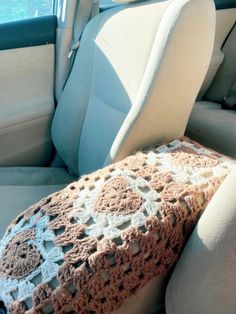 a crocheted blanket sitting on top of a car seat in front of a window