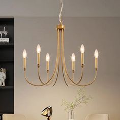 a chandelier hanging over a dining room table with chairs and vases on it