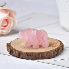 two pink gummy bears sitting on top of a piece of wood next to flowers