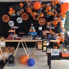 an orange and black birthday party with balloons, desserts, and decorations on the wall