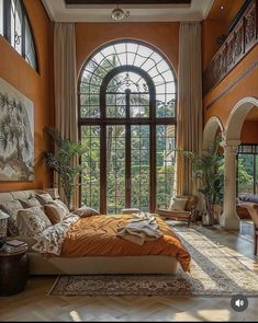 a large bedroom with an arched window and orange bedding in front of a painting on the wall