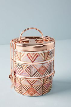 a pink and gold patterned box on a white surface with the lid open to show it's handles