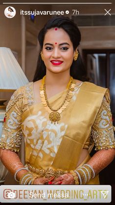 a woman in a yellow and white sari with gold jewelry on her neck, standing next to a lamp