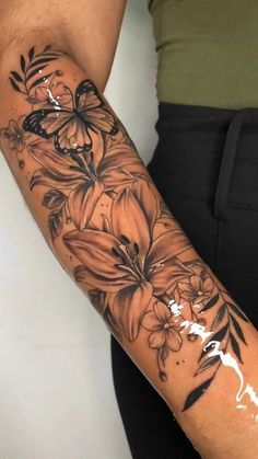 a woman's arm with flowers and butterflies painted on the back of her arm