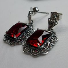 Simulated Red Ruby Solid Sterling Silver Earrings Short Festoon Design#E8z (shorter version) These Victorian reproduction estate earrings are solid sterling silver. These filigree earrings have stunning simulated red ruby gemstones. Each stunning gem is 10mm x 8mm x 5mm in dimension. The earrings are approximately 1/2" x 1" (13mm x 23mm). The unique earrings are marked 925 for solid sterling silver. These lovely earrings were refashioned from an antique Victorian cameo necklace. Quintessentially Classic Red Jewelry As A Gift, Classic Red Ruby Earrings, Classic Ruby Red Earrings, Red Classic Jewelry With Matching Earrings, Classic Red Jewelry With Matching Earrings, Elegant Red Hallmarked Earrings, Elegant Red Sterling Silver Jewelry, Nickel-free Ruby Earrings As A Gift, Red Sterling Silver Pierced Earrings