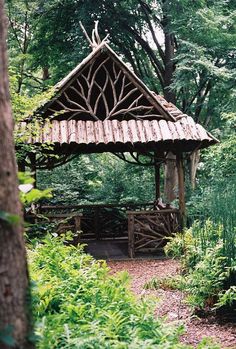 a wooden gazebo in the middle of a forest