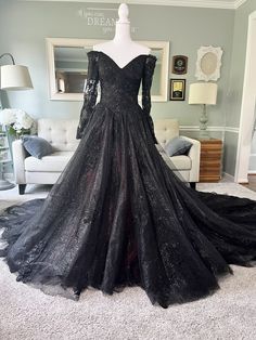 a black dress is on display in a room with white carpet and couches,