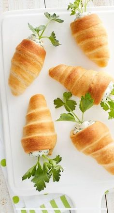 four croissants on a white tray with green garnish and parsley